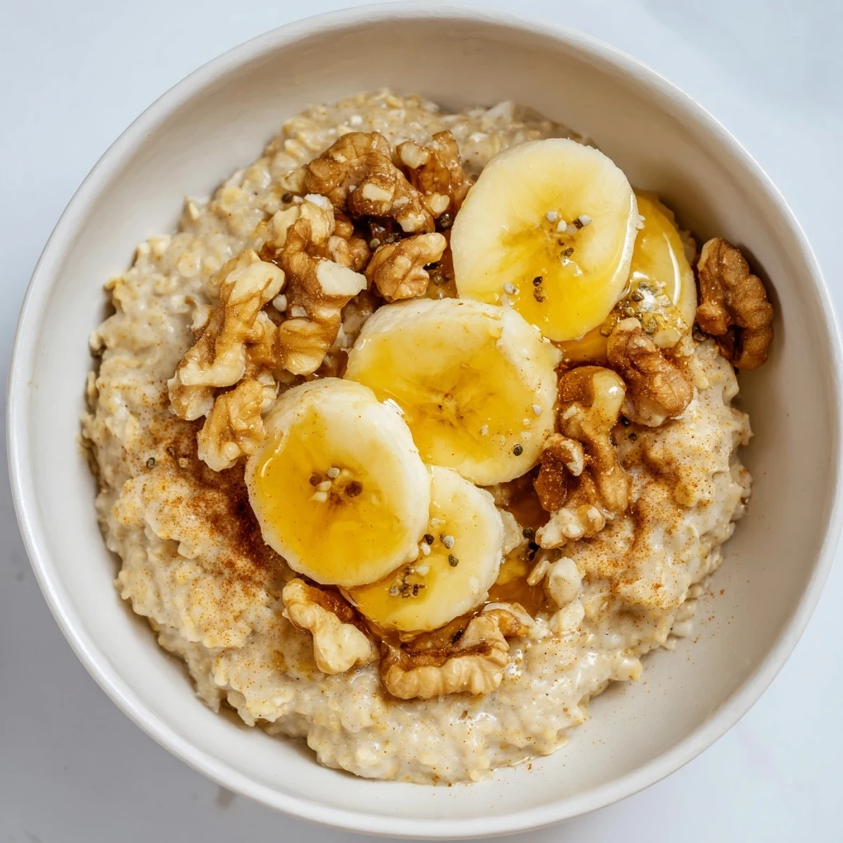 Warm bowl of 2-minute Microwave Banana Oats, ready to eat with sliced bananas and cinnamon sprinkled on top.