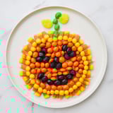 Halloween delight: this Jack-o-Lantern Candy Board features orange, green, and black candies arranged beautifully.