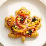 Golden, baked Fall Foliage Maple Leaf Mini Pizzas on a parchment paper-lined baking sheet, smelling delicious.