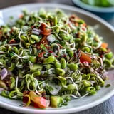 Farbenfroher Sprouted Seed Salad mit spröden Sprossen, Karottenraspeln und einem zitronigen Dressing.