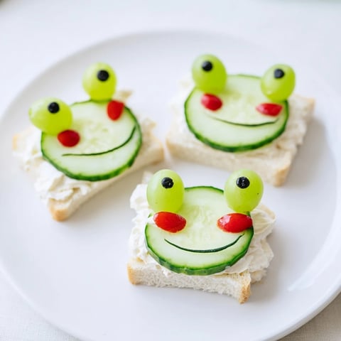 Frog-shaped Prince Charming Froggy Sandwich Cutouts, delightfully decorated with grape eyes and tomato cheeks.