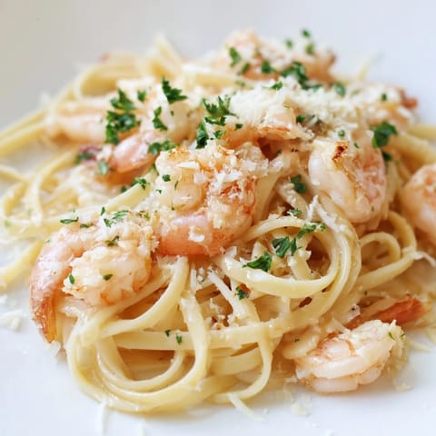Freshly chopped parsley garnishes the skillet of Creamy Garlic Shrimp Pasta, served with lemon wedges.