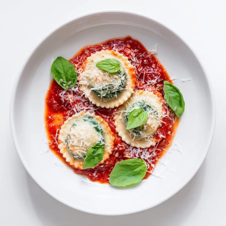 Abendessen-Idee: Spinat Ricotta Ravioli mit würziger Marinara und frischem Parmesan auf dem Teller.