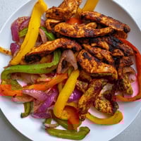 Saftige Sheet-Pan Chicken Fajitas, serviert auf warmen Tortillas mit frischem Cilantro und Limettenspalten.
